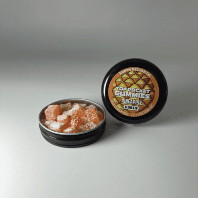 Earth Nectar Co. Top Pocket Gummies in Pineapple, open tin of THC mini gummies beside the sealed tin