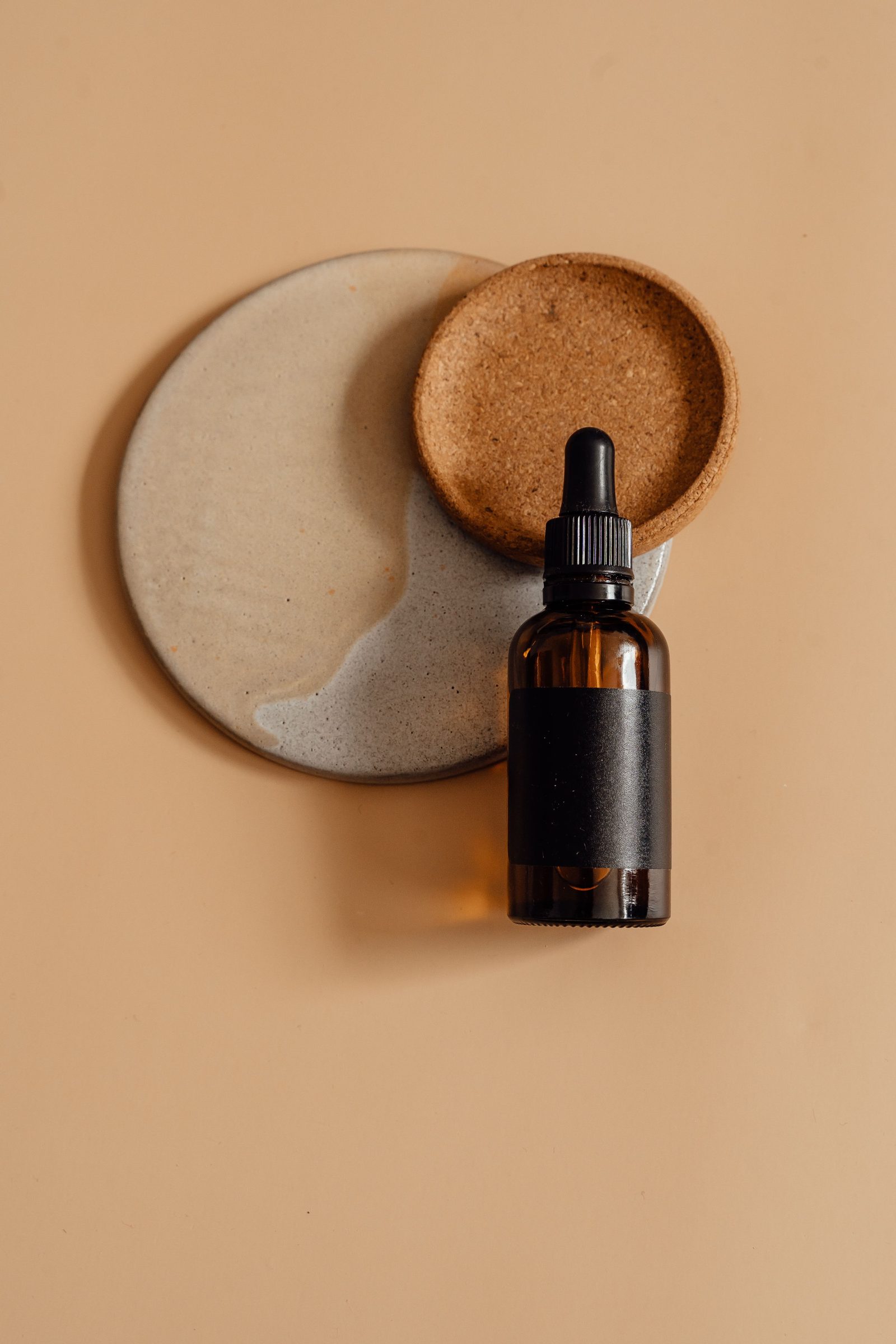 An amber glass cannabis oil bottle stored on a wooden tray in soft light.